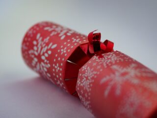 Close-up of a decorative red Christmas cracker with white snowflake patterns and a shiny bow.
